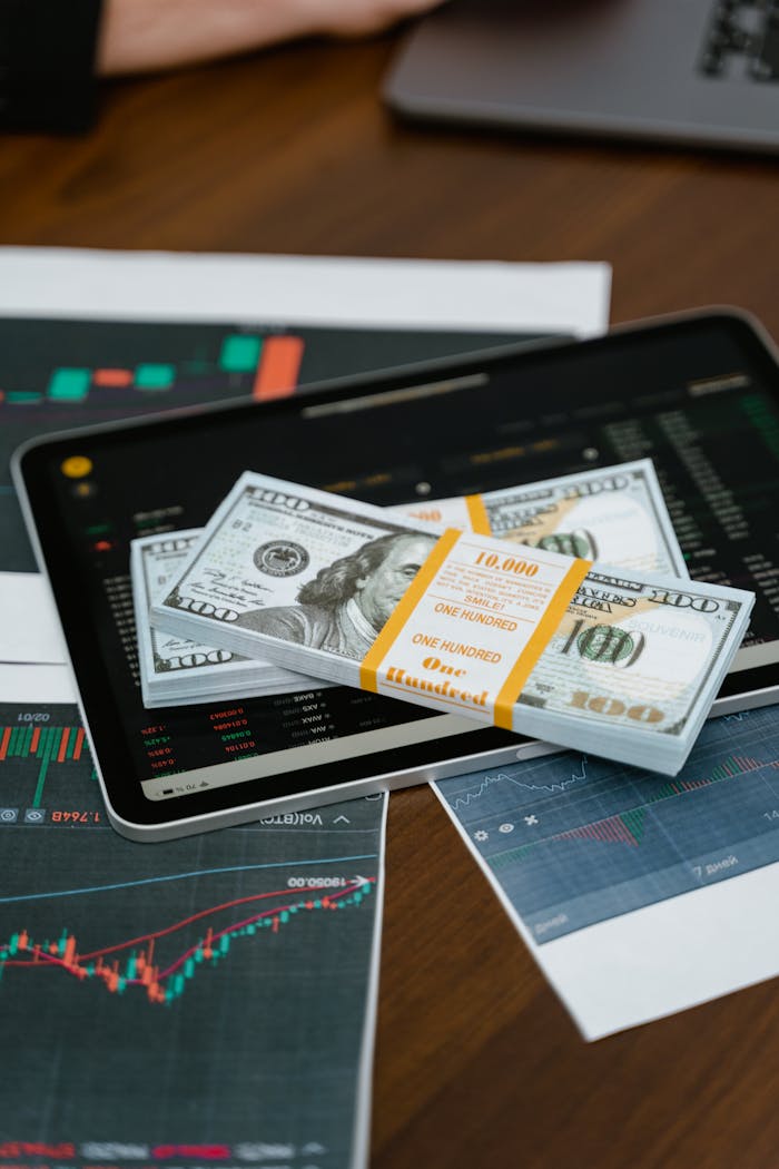 The Smart Way to Use Business Loans for Expansion Stack of $100 bills placed on a tablet with financial graphs, symbolizing digital finance.